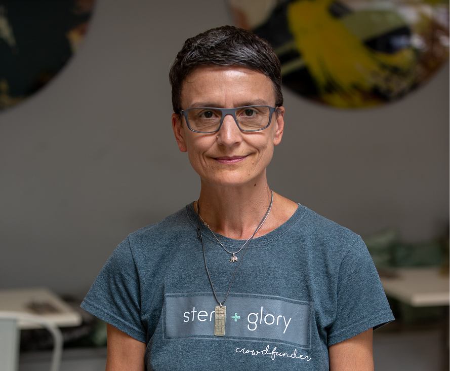 Headshot of female business owner wearing glasses and a grey t-shirt